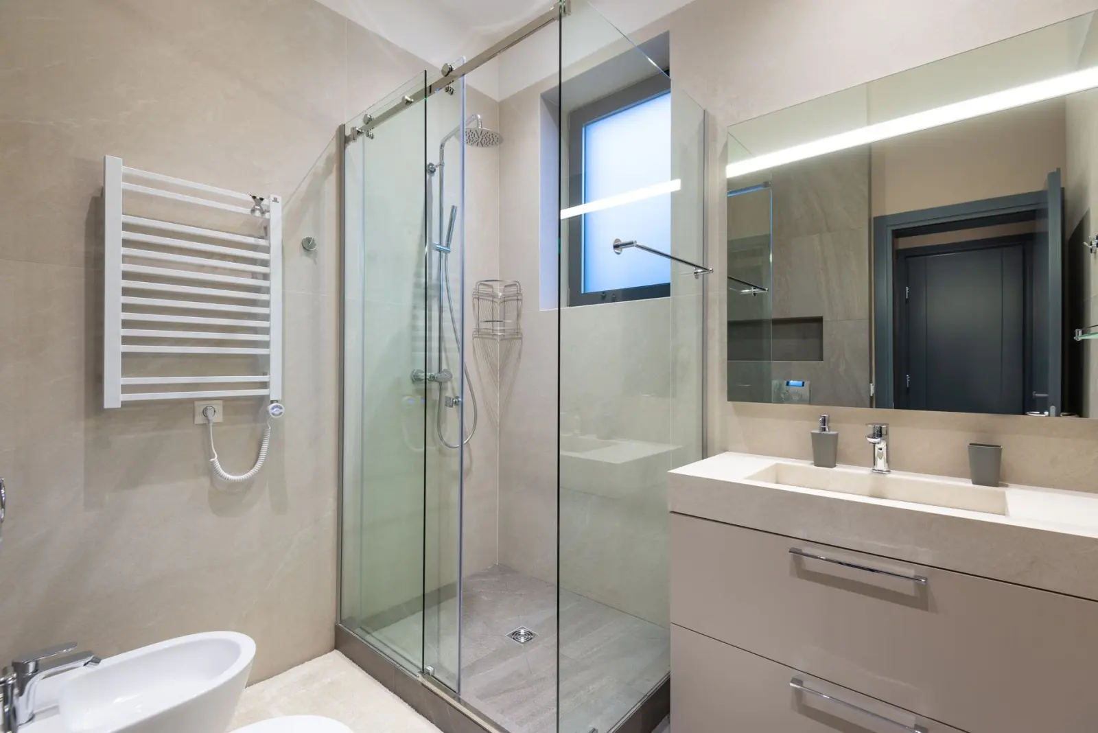 Modern glass-walled shower with a mirror and sink in a minimalist bathroom