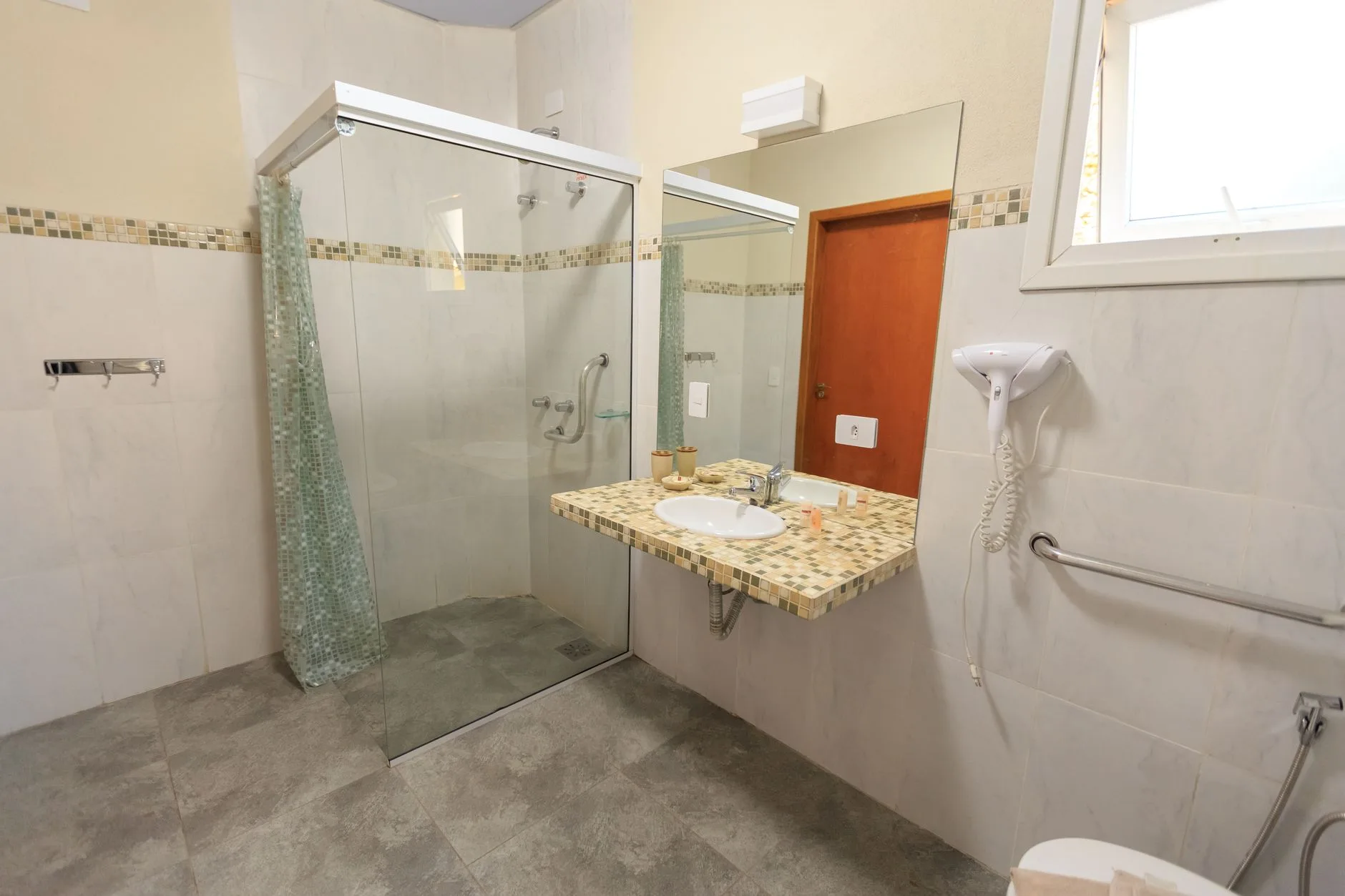 Spacious accessible bathroom with a curbless glass shower and modern fixtures