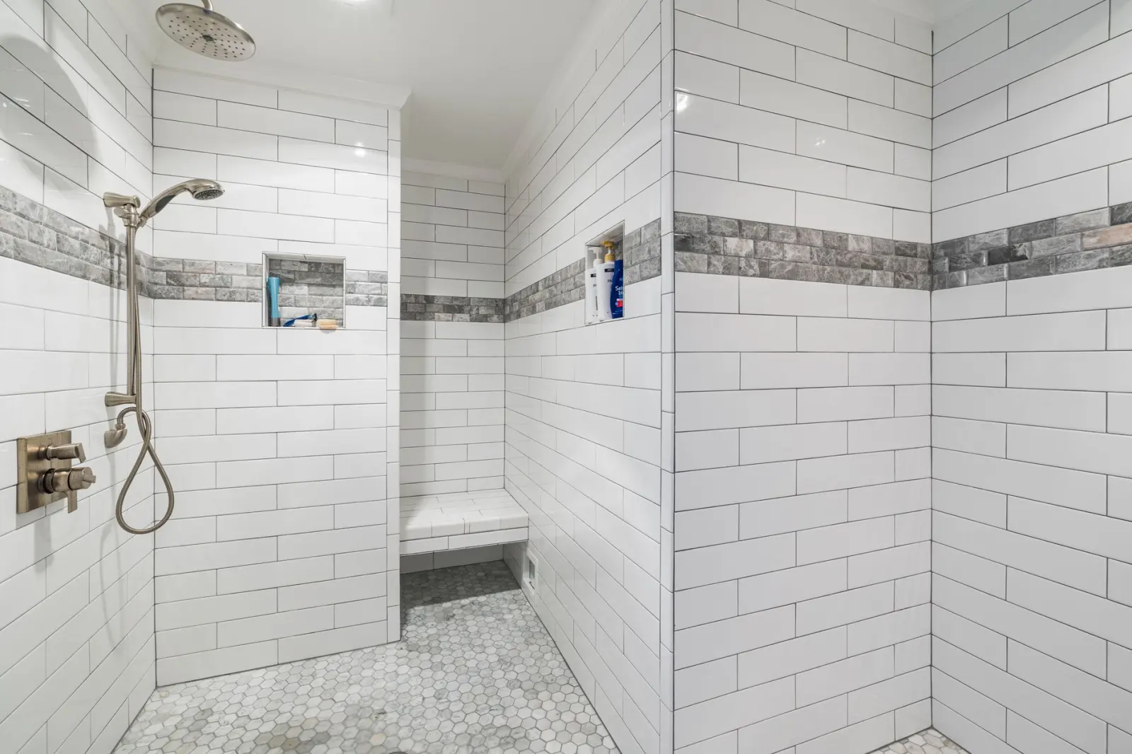 Sleek white tiled walk-in shower with a flush mosaic floor and modern fixtures