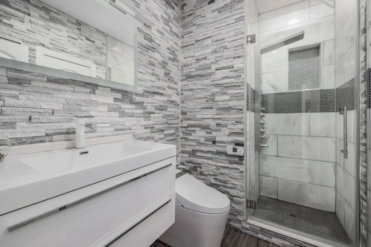 Modern bathroom with a glass-enclosed shower and stone tile walls